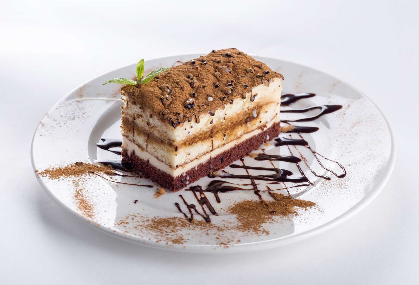 Slice of cake on a white plate with chocolate sauce, compressed to 100 KB